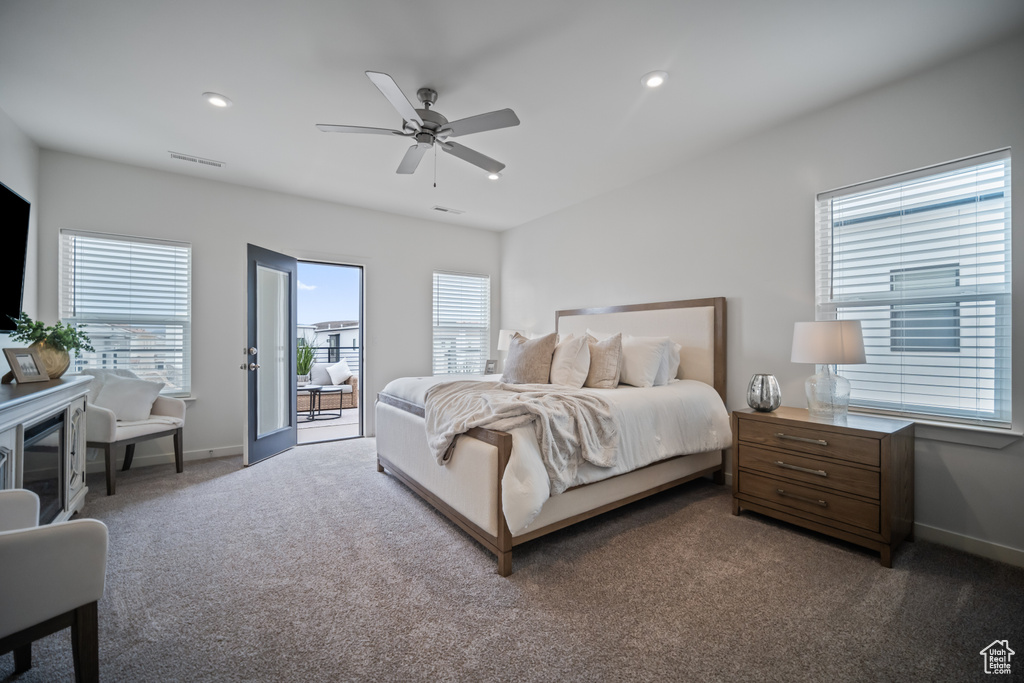 Carpeted bedroom featuring multiple windows, access to outside, and ceiling fan