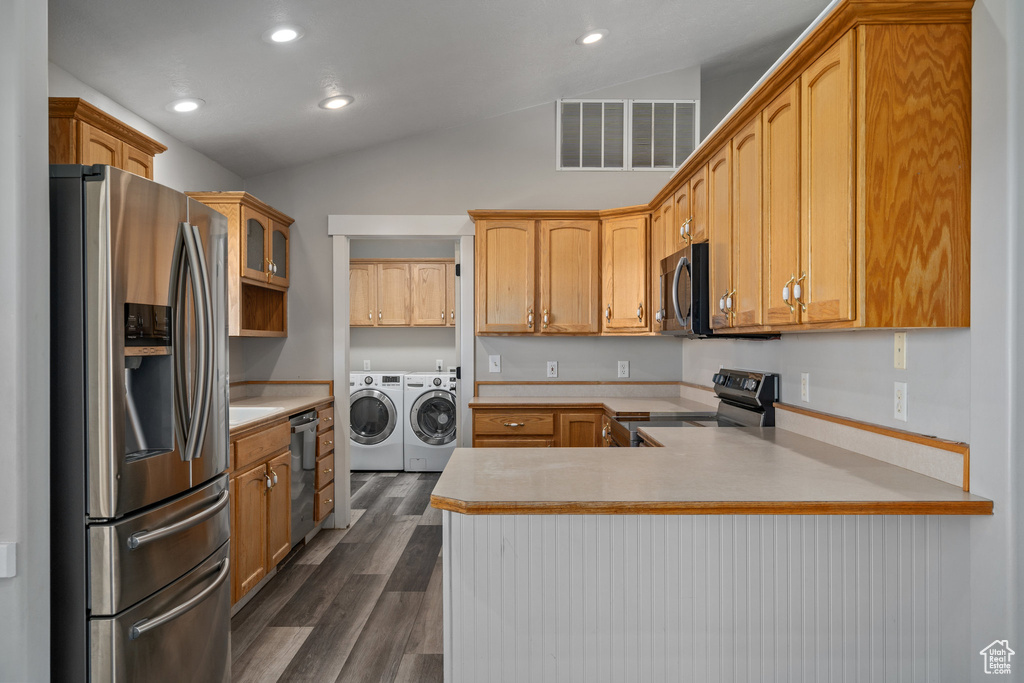 Kitchen featuring appliances with stainless steel finishes, lofted ceiling, kitchen peninsula, separate washer and dryer, and dark hardwood / wood-style floors