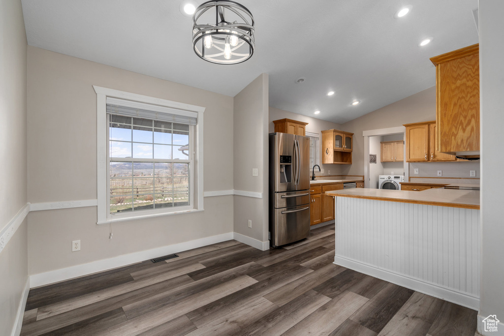 Kitchen with an inviting chandelier, dark wood-type flooring, vaulted ceiling, washer / dryer, and stainless steel refrigerator with ice dispenser