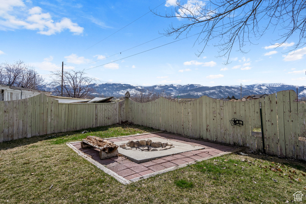 View of yard with an outdoor fire pit, a mountain view, and a patio area
