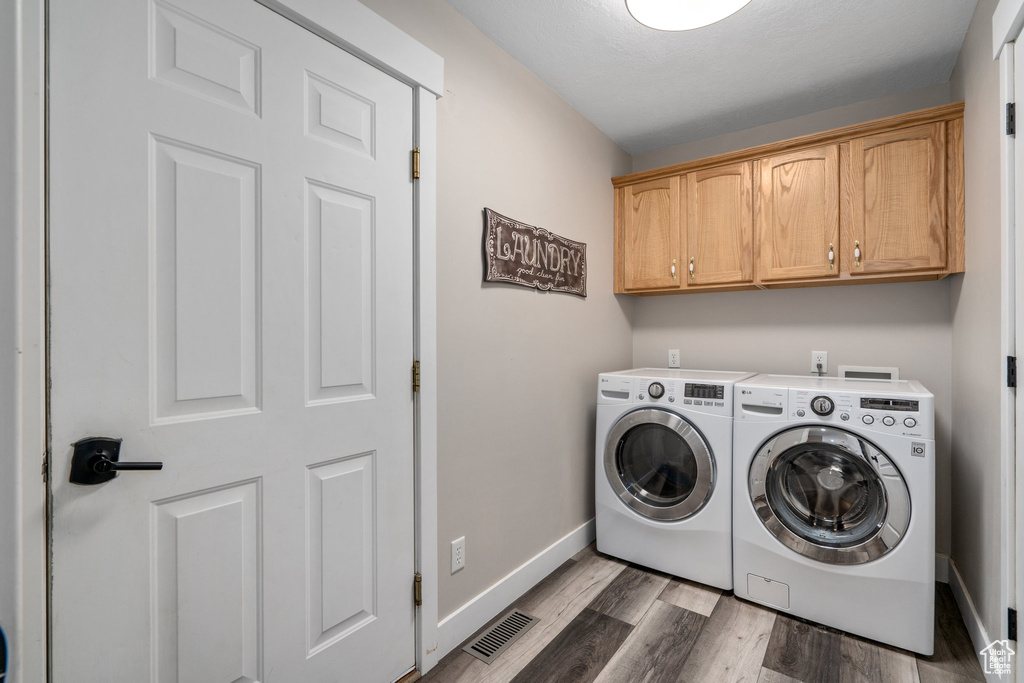 Washroom featuring hookup for a washing machine, cabinets, light hardwood / wood-style floors, and independent washer and dryer