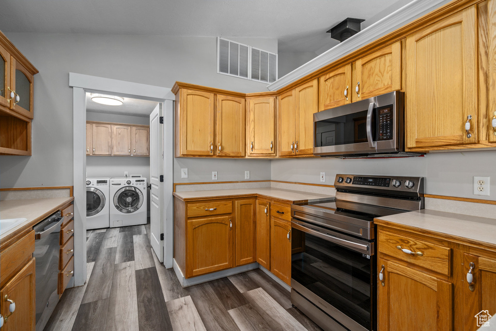 Kitchen featuring dark hardwood / wood-style flooring, washing machine and clothes dryer, stainless steel appliances, and vaulted ceiling