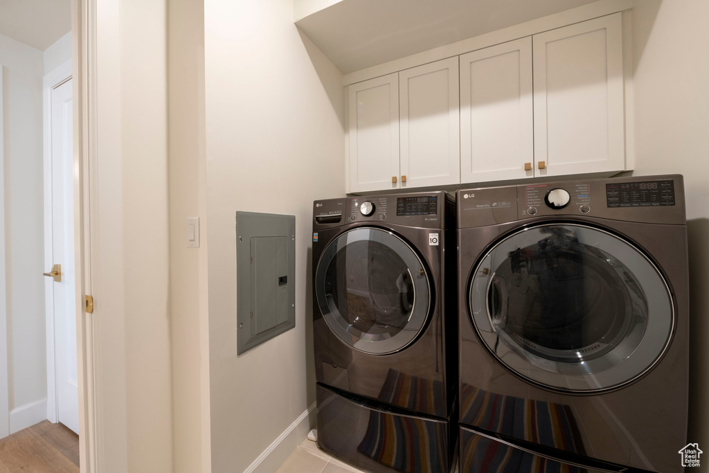 Laundry room with washer and dryer, light hardwood / wood-style flooring, and cabinets