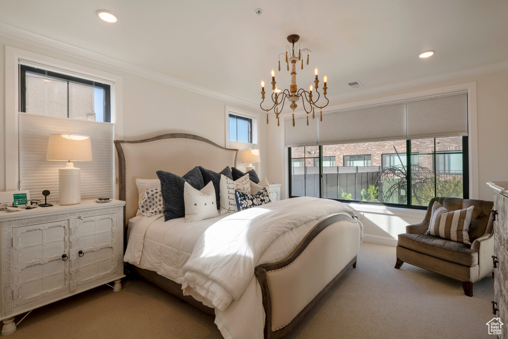 Carpeted bedroom featuring multiple windows, crown molding, and a notable chandelier