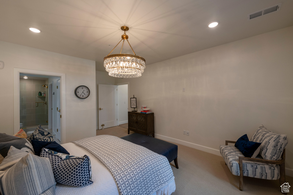 Bedroom with an inviting chandelier, light colored carpet, and connected bathroom