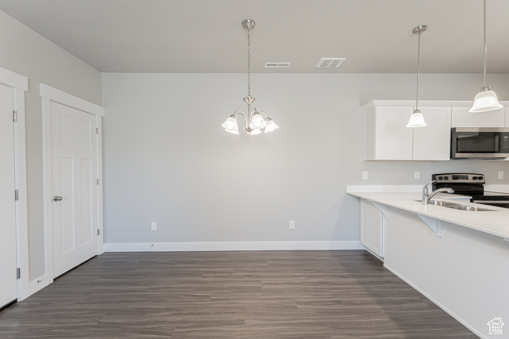 Kitchen featuring appliances with stainless steel finishes, hanging light fixtures, dark hardwood / wood-style floors, and white cabinetry