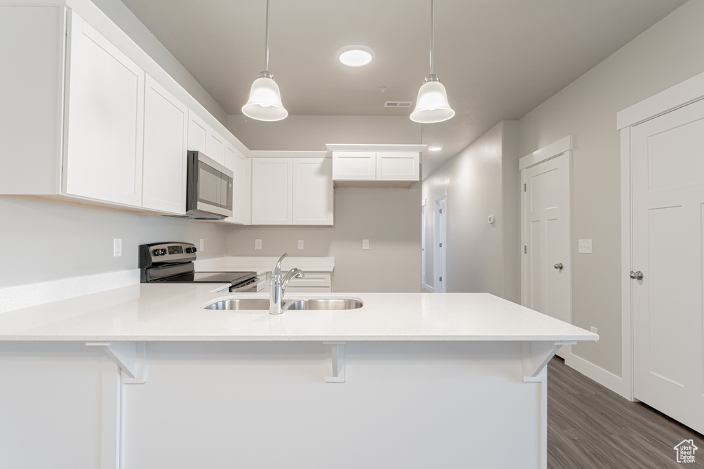 Kitchen featuring range with electric cooktop, sink, pendant lighting, white cabinets, and dark hardwood / wood-style floors