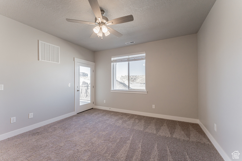 Unfurnished room with a textured ceiling, carpet, and ceiling fan