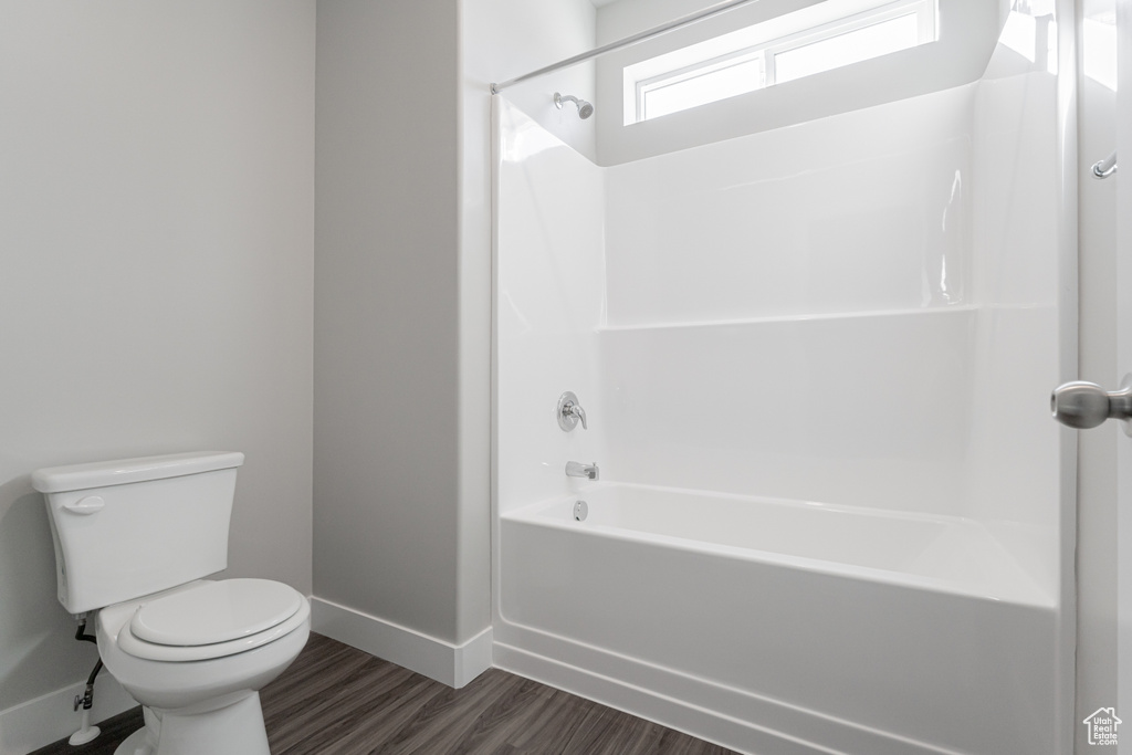 Bathroom featuring toilet, hardwood / wood-style floors, and bathing tub / shower combination