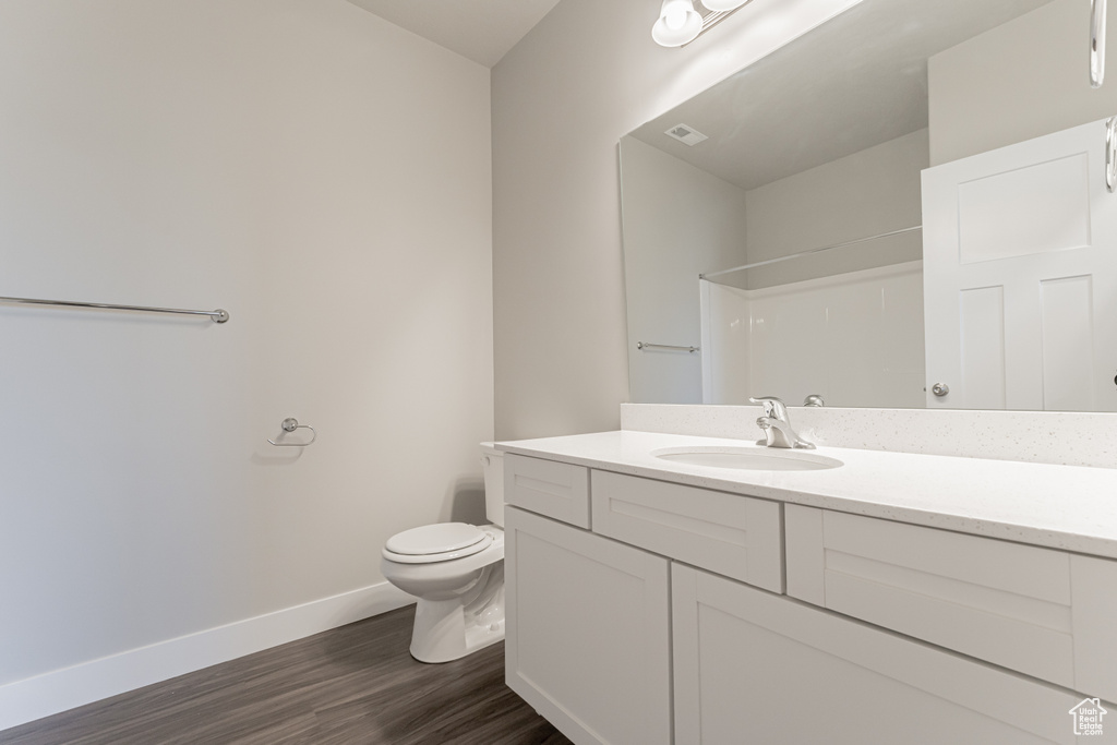 Bathroom with toilet, walk in shower, hardwood / wood-style flooring, and vanity