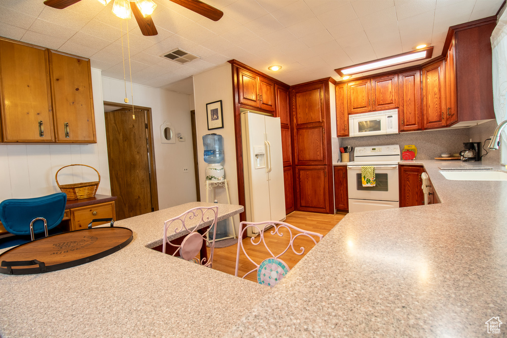 Kitchen with ceiling fan, sink, light wood-type flooring, and white appliances