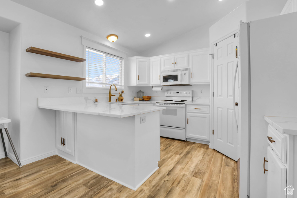 Kitchen featuring white cabinets, light wood-type flooring, and white appliances