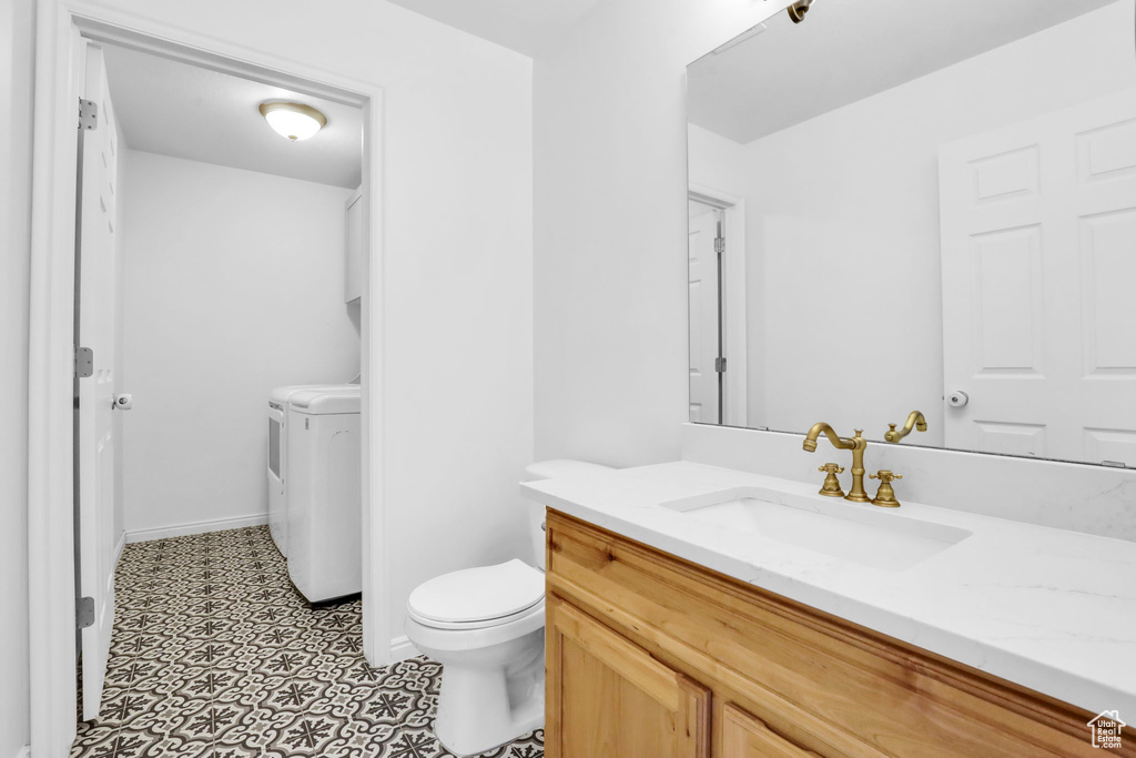 Bathroom with tile floors, washer and clothes dryer, vanity, and toilet