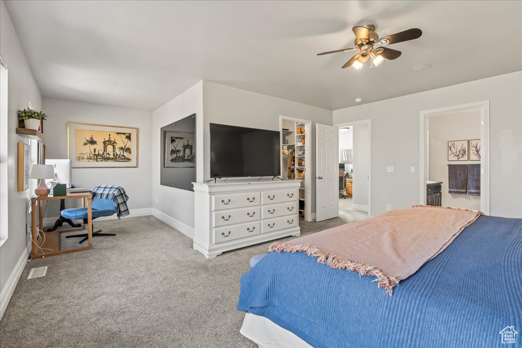 Bedroom featuring ceiling fan, light colored carpet, a closet, ensuite bath, and a walk in closet
