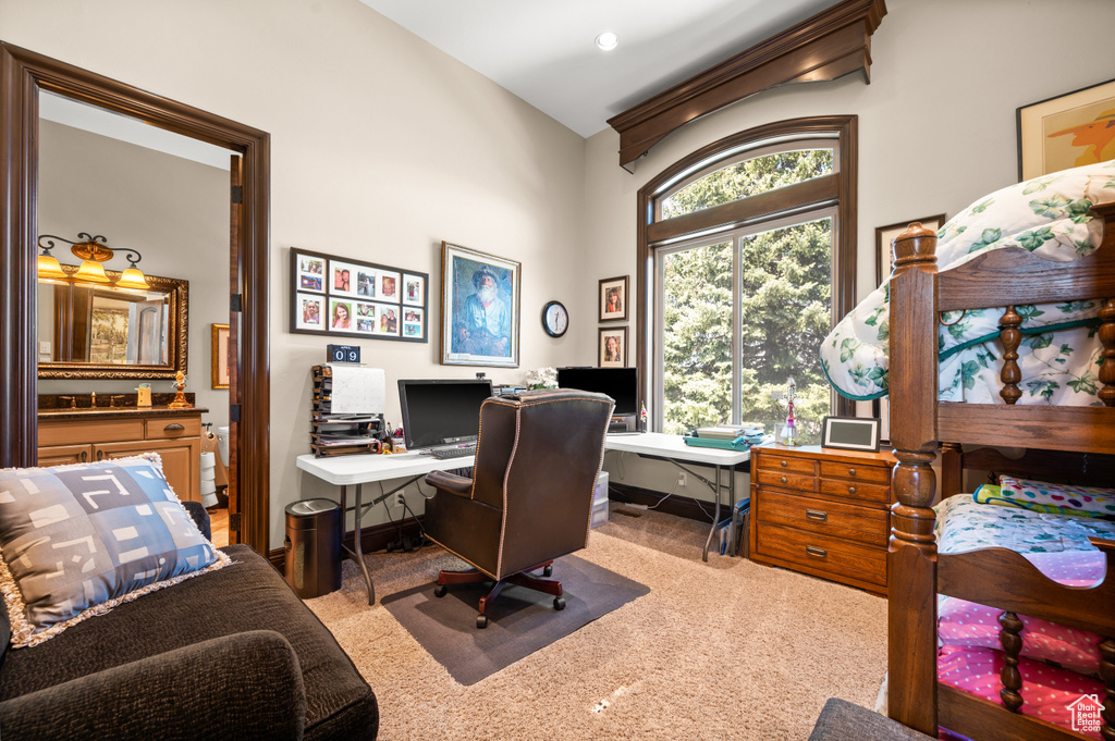 Office space with vaulted ceiling and light colored carpet