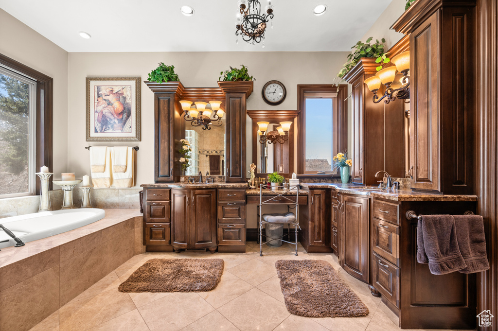 Bathroom with vanity, tiled tub, tile floors, and a chandelier