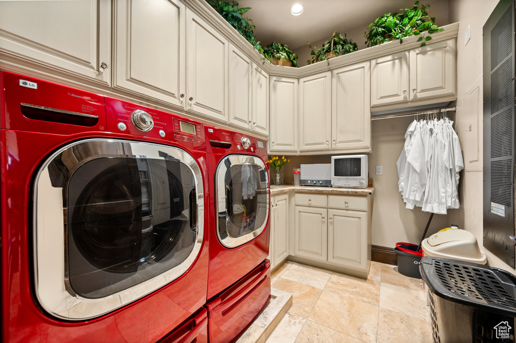 Washroom with independent washer and dryer, light tile flooring, and cabinets