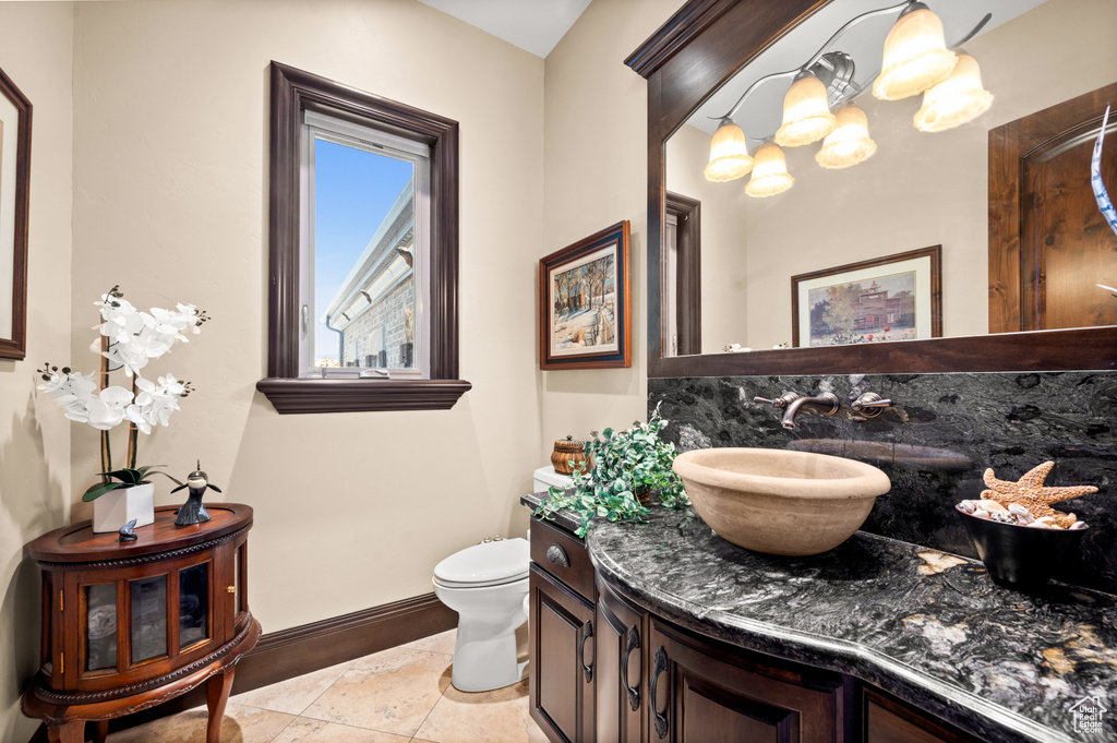 Bathroom with large vanity, toilet, tile floors, and a chandelier