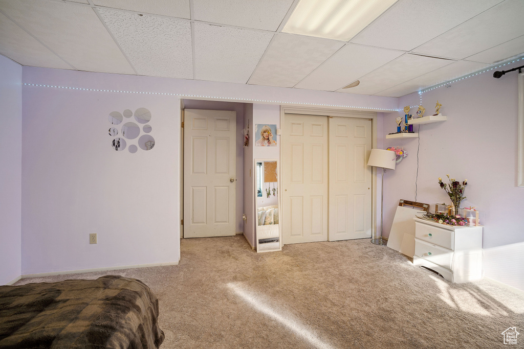 Bedroom featuring a closet, a drop ceiling, and light colored carpet
