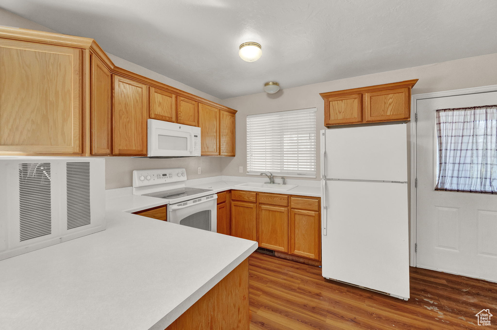 Kitchen featuring sink, white appliances, hardwood / wood-style flooring, and kitchen peninsula