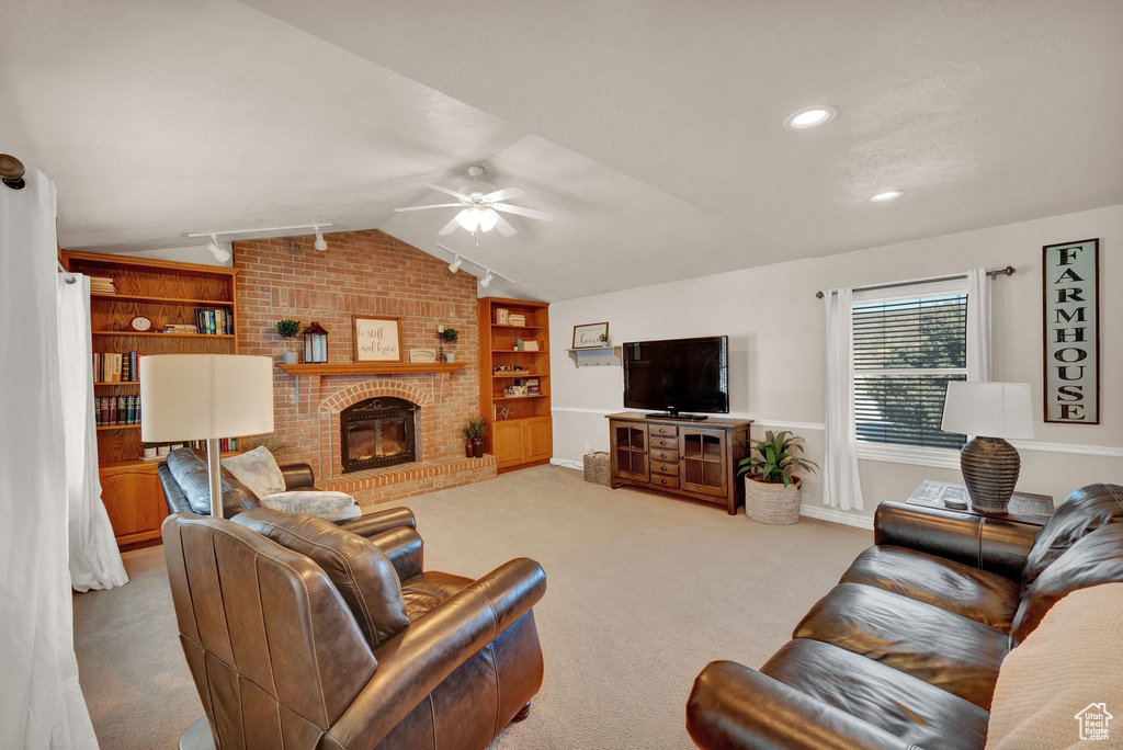 Living room with ceiling fan, light carpet, lofted ceiling, built in shelves, and a fireplace