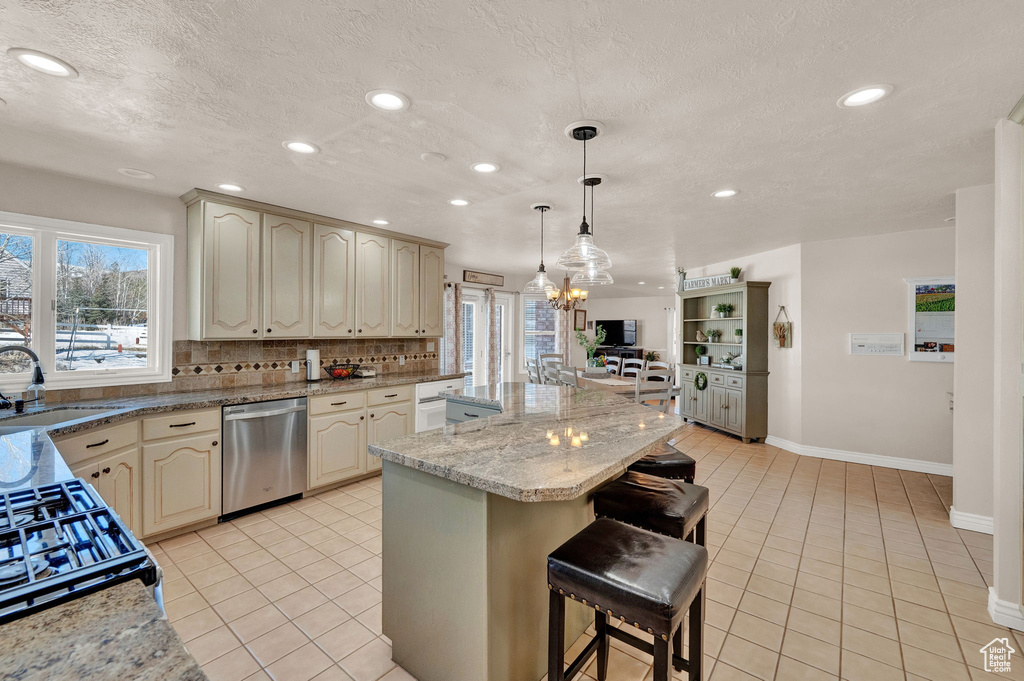 Kitchen featuring a kitchen island, a chandelier, tasteful backsplash, dishwasher, and decorative light fixtures