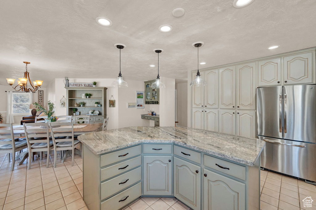 Kitchen with a notable chandelier, pendant lighting, a center island, and stainless steel fridge