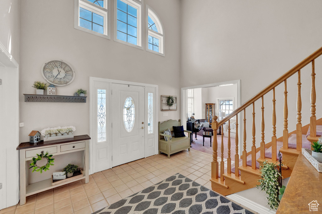 Foyer with a high ceiling, a healthy amount of sunlight, and light tile flooring