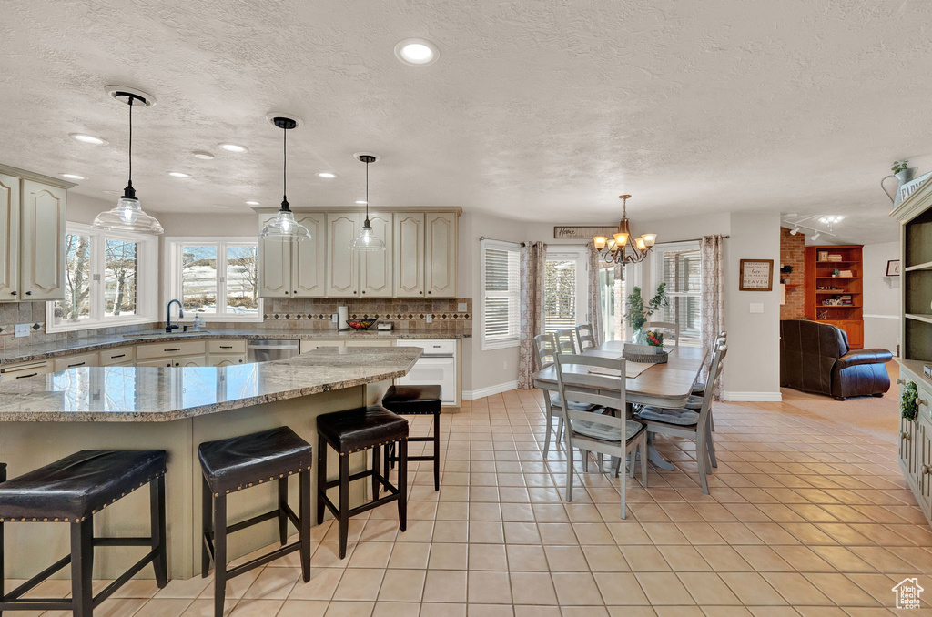 Kitchen featuring a healthy amount of sunlight, pendant lighting, a notable chandelier, and tasteful backsplash