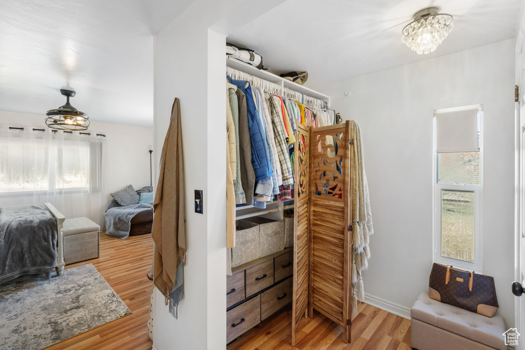 Spacious closet with light hardwood / wood-style flooring and a chandelier
