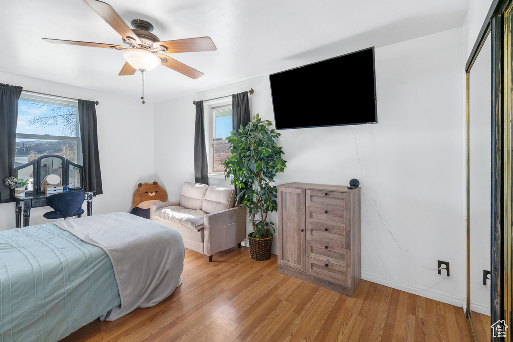 Bedroom with multiple windows, ceiling fan, and light hardwood / wood-style floors