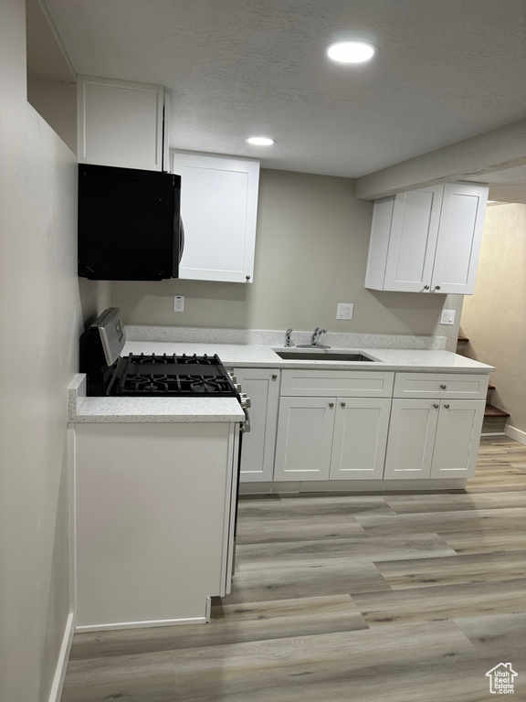 Kitchen with sink, white cabinets, and light wood-type flooring