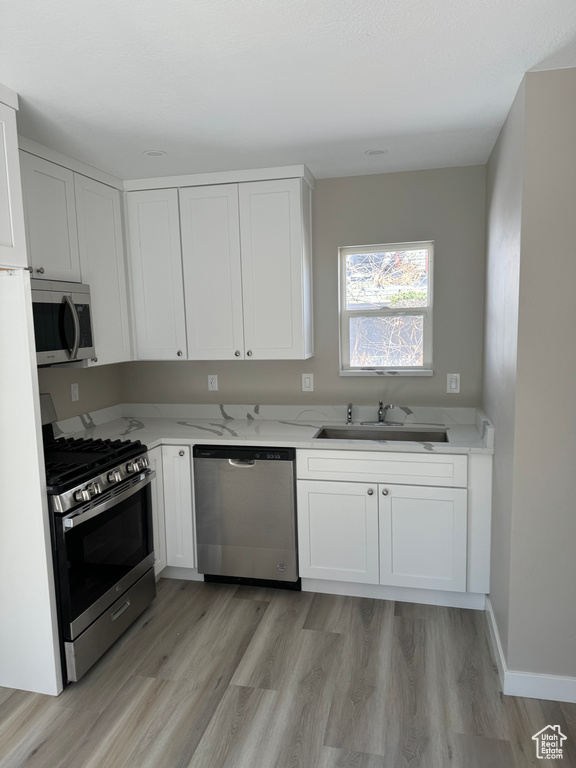 Kitchen featuring white cabinets, appliances with stainless steel finishes, light hardwood / wood-style flooring, and sink
