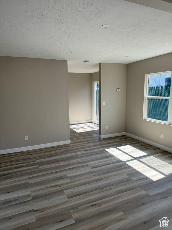 Empty room with a textured ceiling and hardwood / wood-style flooring