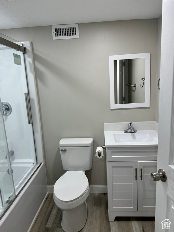 Full bathroom featuring vanity, shower / bath combination with glass door, toilet, and hardwood / wood-style flooring