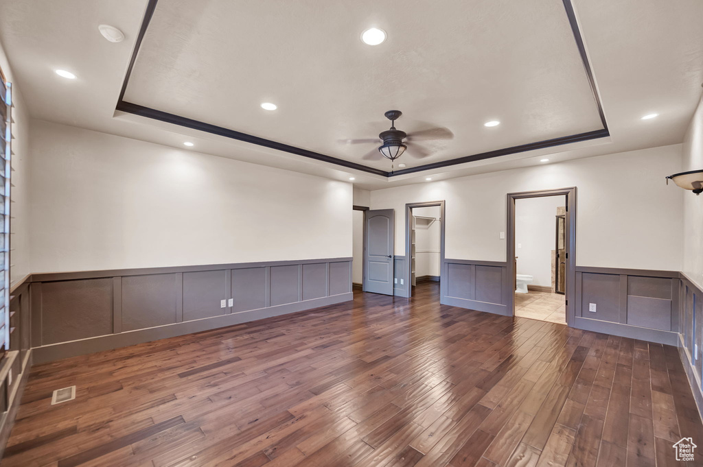 Unfurnished room with a tray ceiling, dark wood-type flooring, and ceiling fan