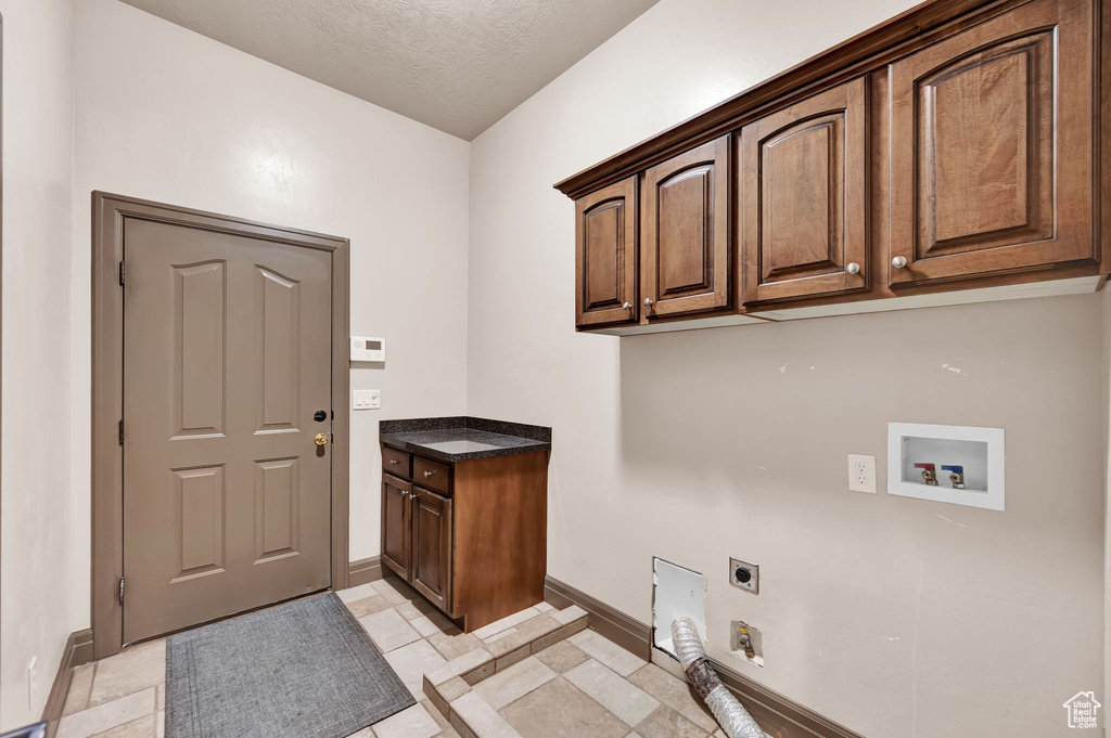 Washroom featuring washer hookup, electric dryer hookup, a textured ceiling, cabinets, and light tile floors