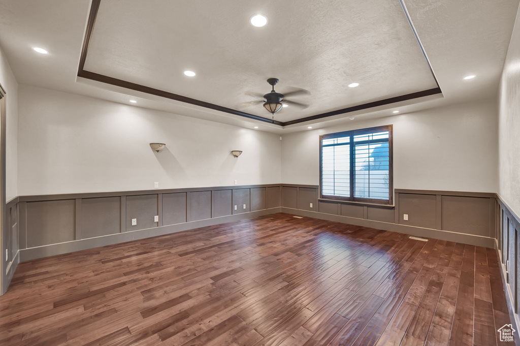 Spare room with a tray ceiling, ceiling fan, and dark hardwood / wood-style floors