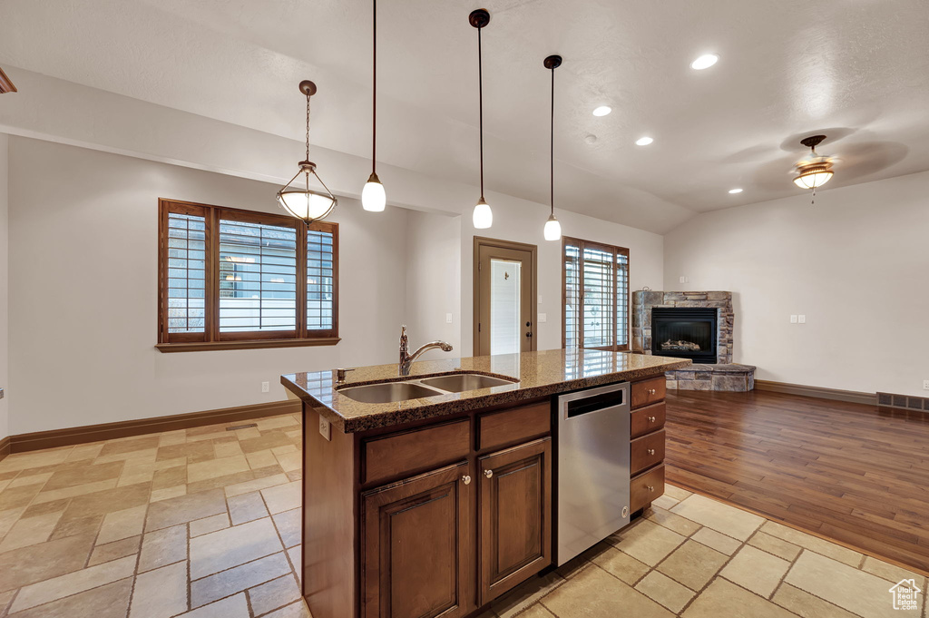 Kitchen featuring sink, decorative light fixtures, light wood-type flooring, ceiling fan, and a stone fireplace