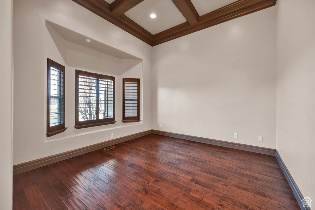 Empty room featuring coffered ceiling, beam ceiling, and dark hardwood / wood-style floors