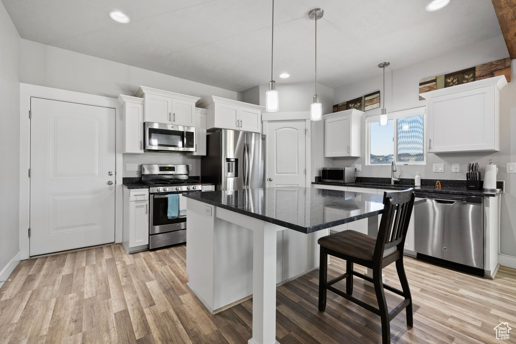 Kitchen with white cabinetry, a center island, stainless steel appliances, and light hardwood / wood-style flooring