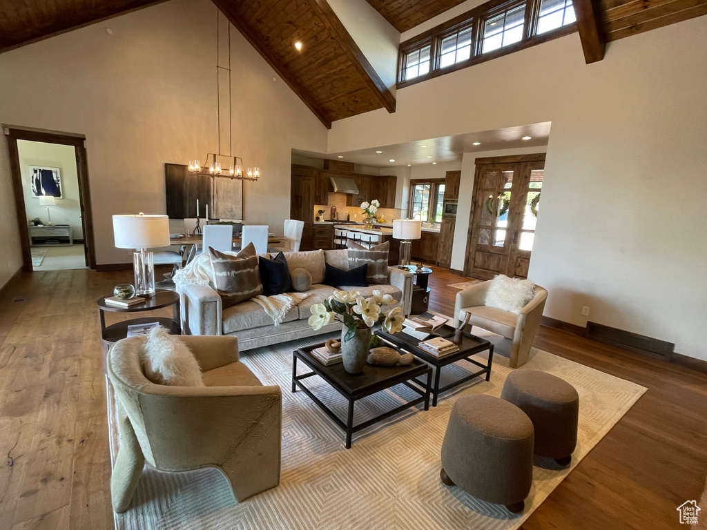 Living room with hardwood / wood-style flooring, beamed ceiling, high vaulted ceiling, and a notable chandelier