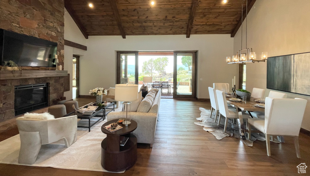 Living room featuring beamed ceiling, wooden ceiling, a fireplace, a chandelier, and hardwood / wood-style flooring