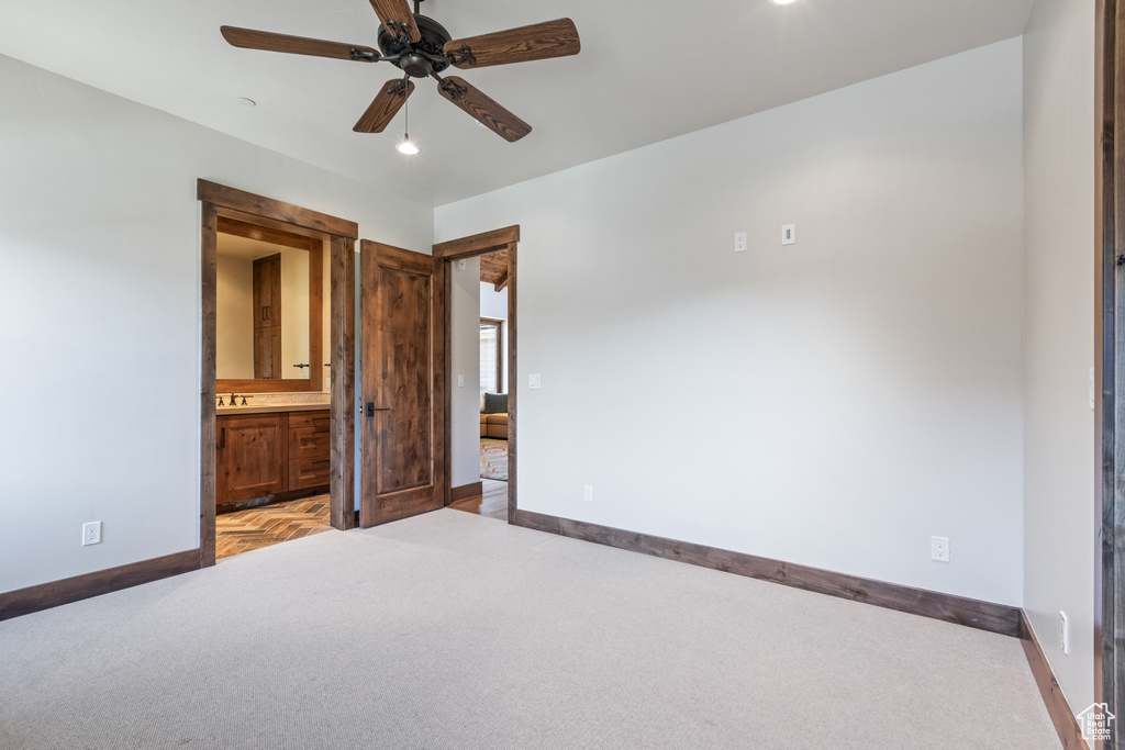 Unfurnished bedroom with light colored carpet, connected bathroom, and ceiling fan