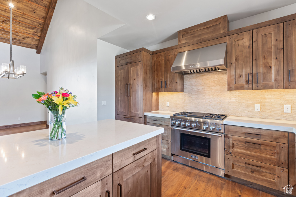 Kitchen featuring light hardwood / wood-style floors, a notable chandelier, pendant lighting, wall chimney exhaust hood, and high end range