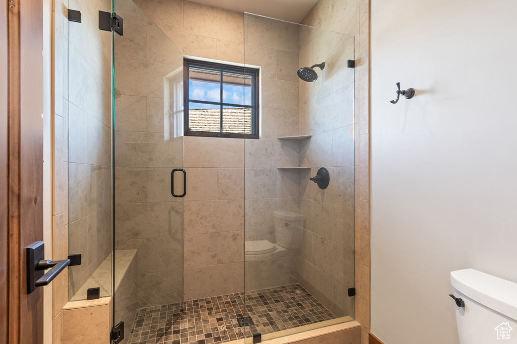 Bathroom featuring a shower with shower door and toilet