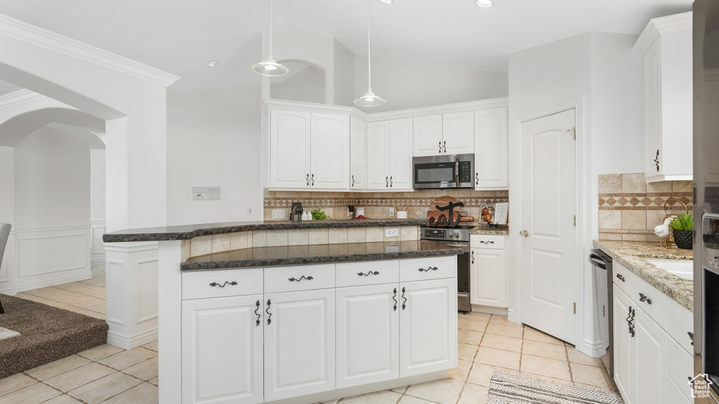 Kitchen with tasteful backsplash, white cabinets, stainless steel appliances, and light tile floors
