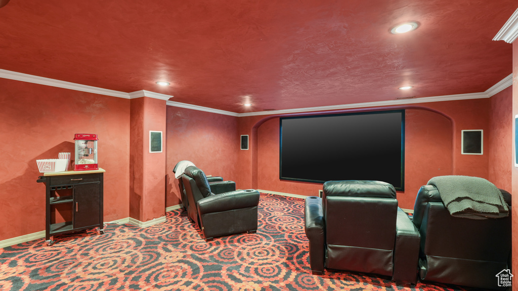 Home theater room with dark carpet and crown molding