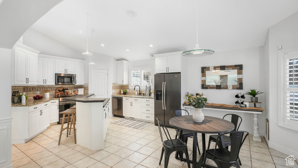 Kitchen featuring white cabinets, pendant lighting, a breakfast bar, stainless steel appliances, and a kitchen island