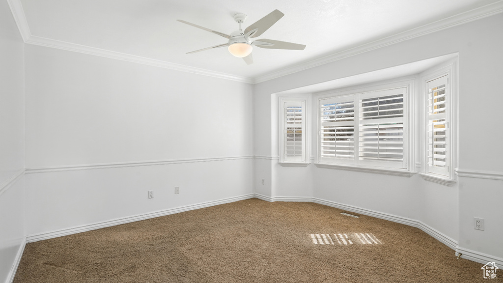 Carpeted spare room with crown molding and ceiling fan